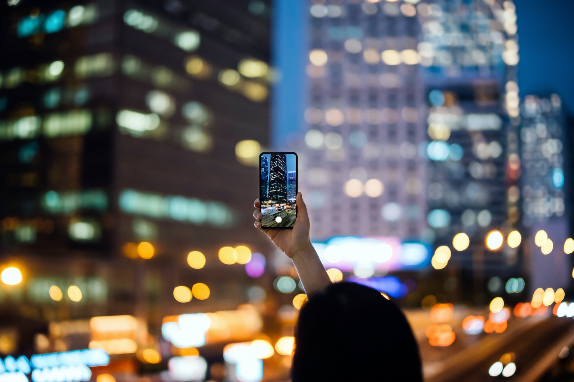 Person taking a picture of city night views with iPhone
