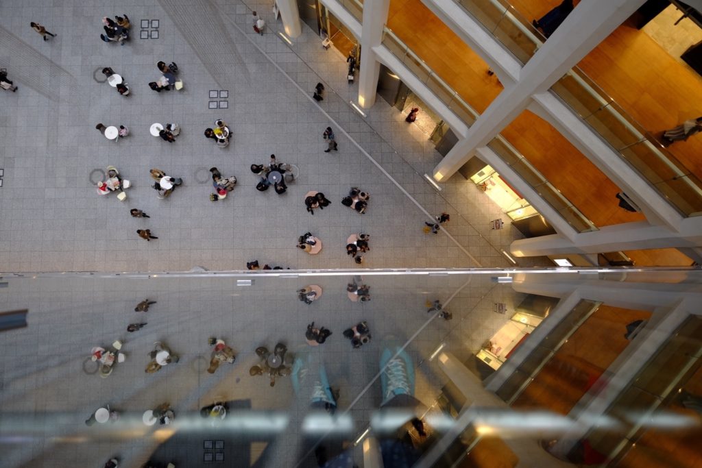 Person taking picture of people leisuring in a shopping mall atrium